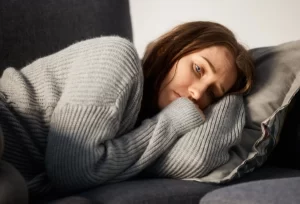 A woman resting on a couch reflecting the physical and mental effects of medication, used to illustrate how long Tramadol stays in the system.
