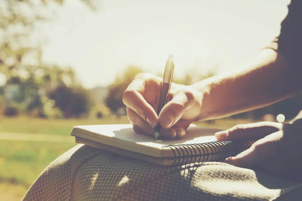 Person writing coping strategies in a journal during addiction recovery