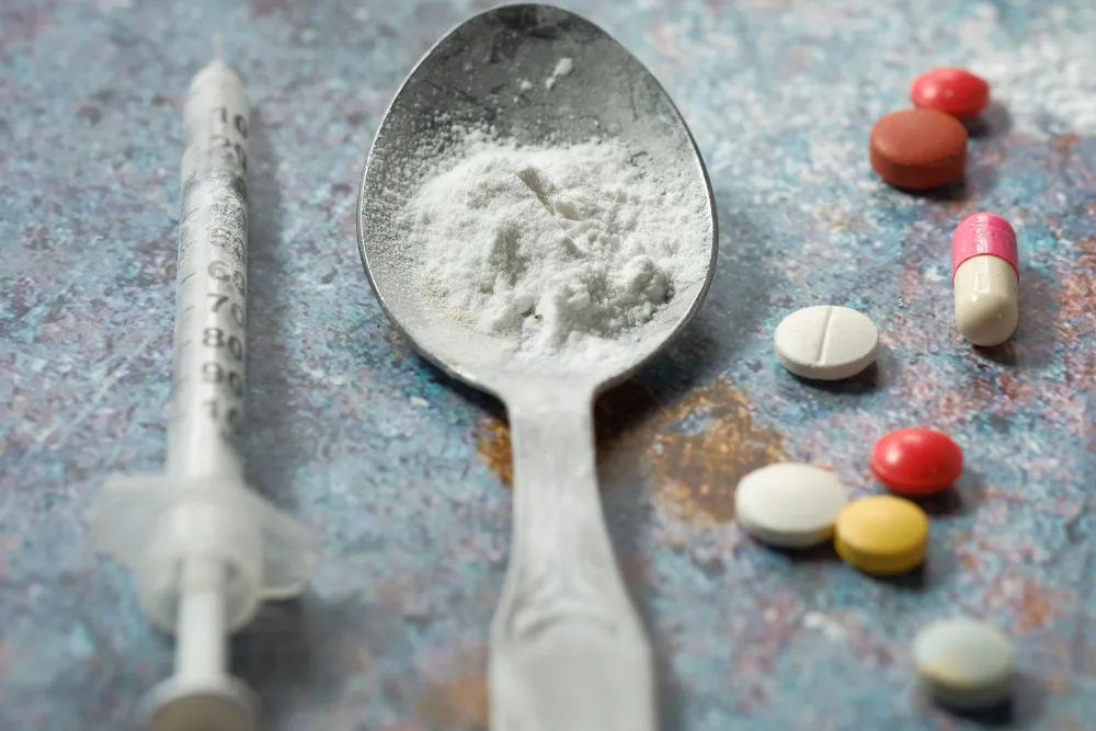 Syringe, white opioid powder, and prescription pills representing fentanyl vs morphine potency and opioid overdose risk