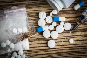 Assorted pills and substances representing upper drugs (stimulants) and downer drugs (depressants) on a table