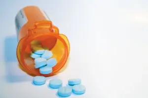Blue opioid pills spilling from a prescription bottle representing fentanyl and comparison with other opioid medications