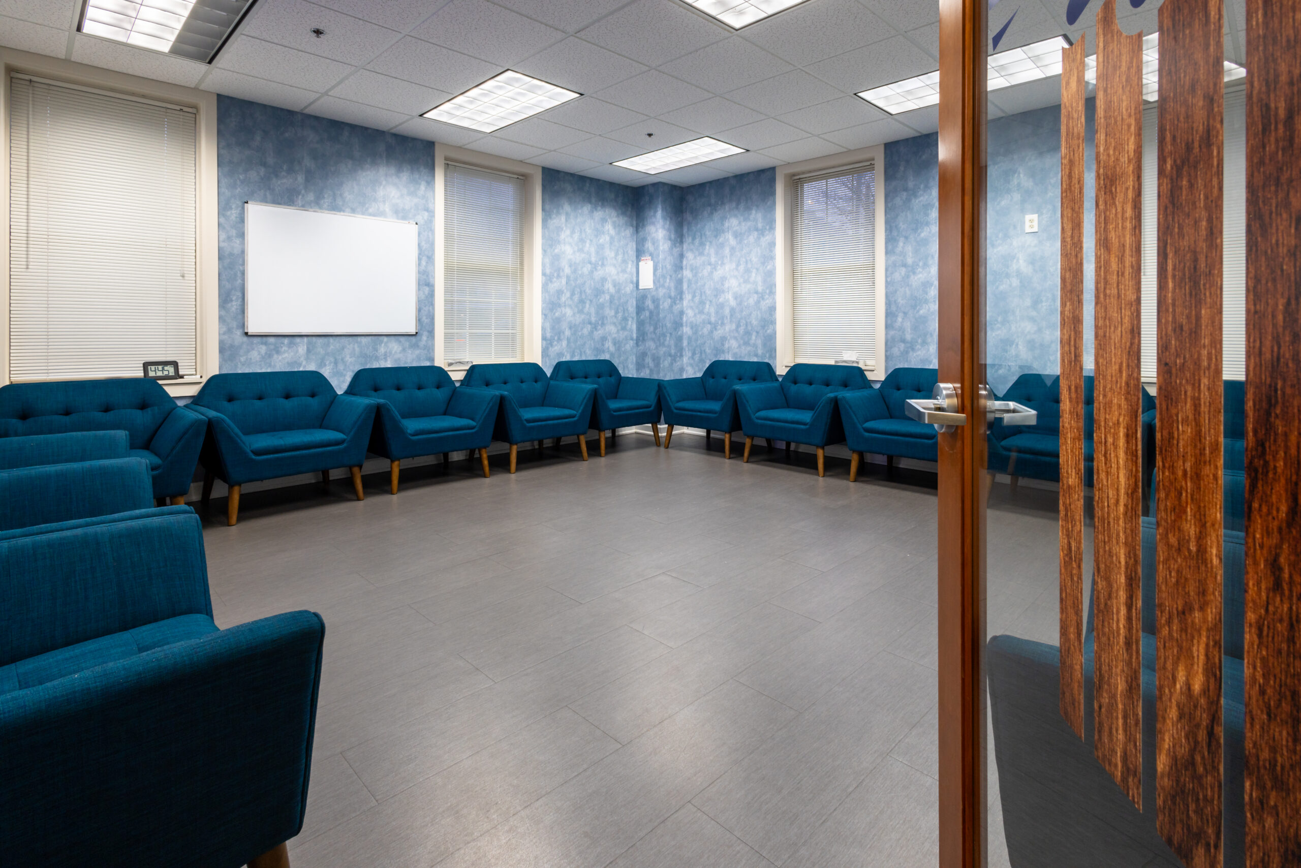 The image depicts a serene indoor therapy area at a luxury addiction treatment facility, featuring comfortable seating surrounded by calming wallpaper, providing a peaceful environment for patients undergoing acute rehabilitation and therapy sessions. This space is designed to support recovery and well-being, allowing patients to heal while participating in talk therapy.