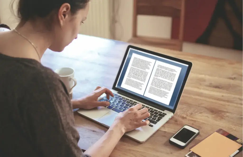 Person writing a sample letter for a drug treatment program on a laptop, representing documentation used in addiction recovery and rehab communication
