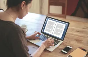 Person writing a sample letter for a drug treatment program on a laptop, representing documentation used in addiction recovery and rehab communication