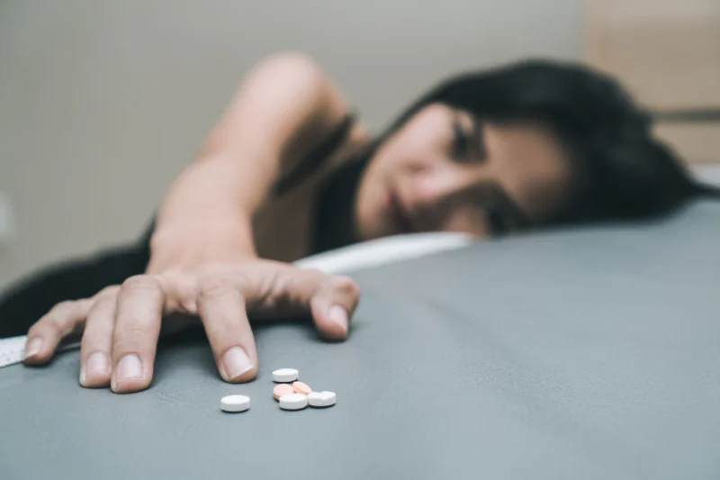 Person reaching for pills symbolizing co-occurring disorders and dual diagnosis involving mental health and substance use