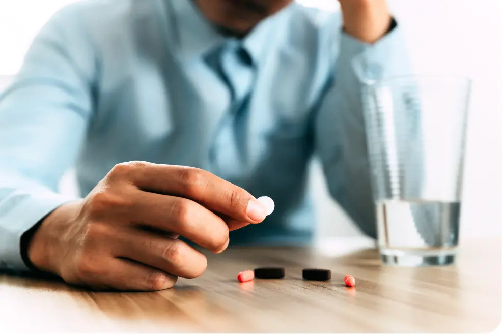 Person holding ibogaine pills beside a glass of water, representing ibogaine treatment for addiction and substance use recovery.